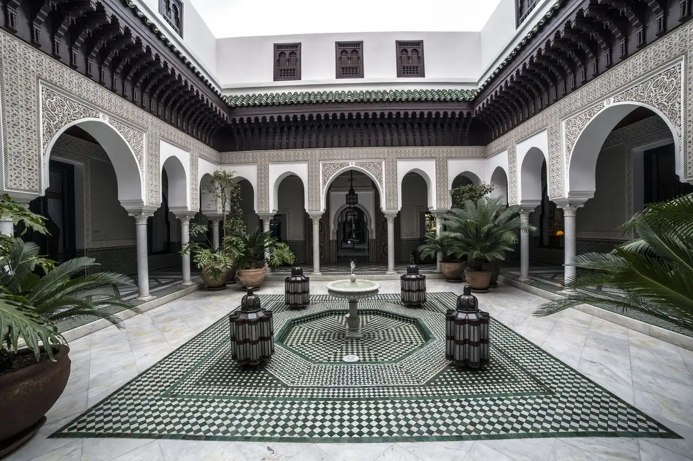 An ornate courtyard with carved arches and a fountain in Marrakech.
