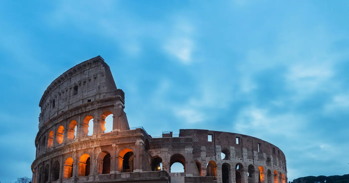 The Colosseum in Rome, stone arches against a blue sky.