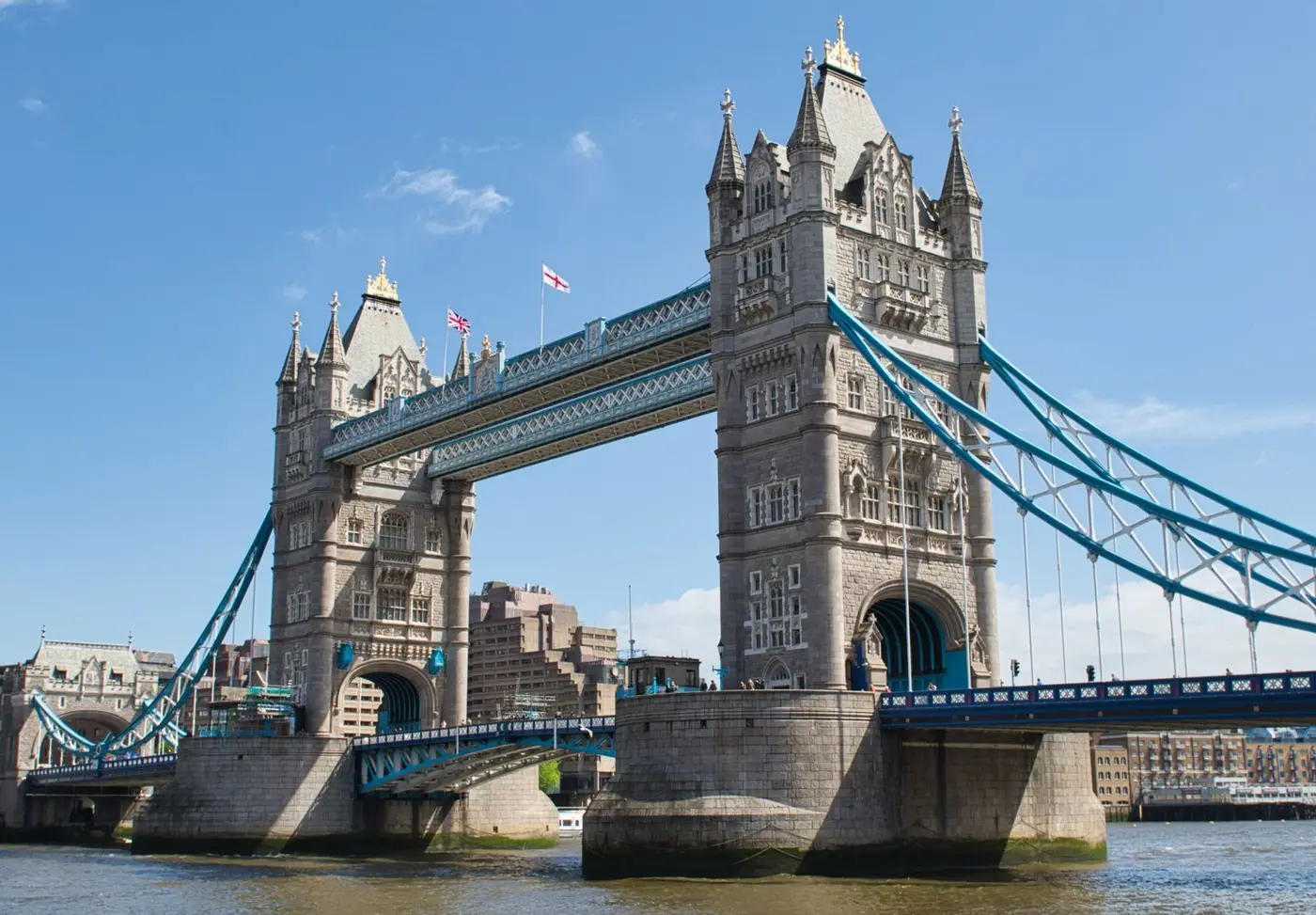 Tower Bridge in London under a clear blue sky, seen from the river.