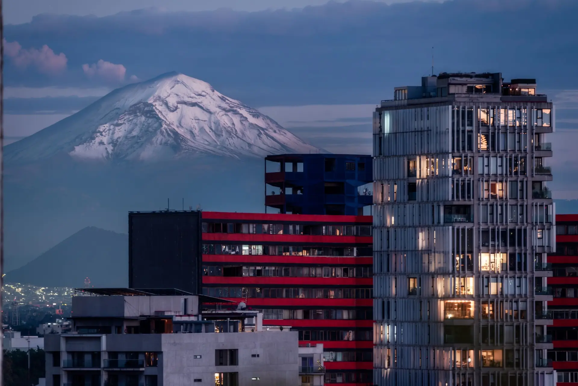 Mexico City at sunset, with the city in front of the snow-tipped peak of Popocatepetl.