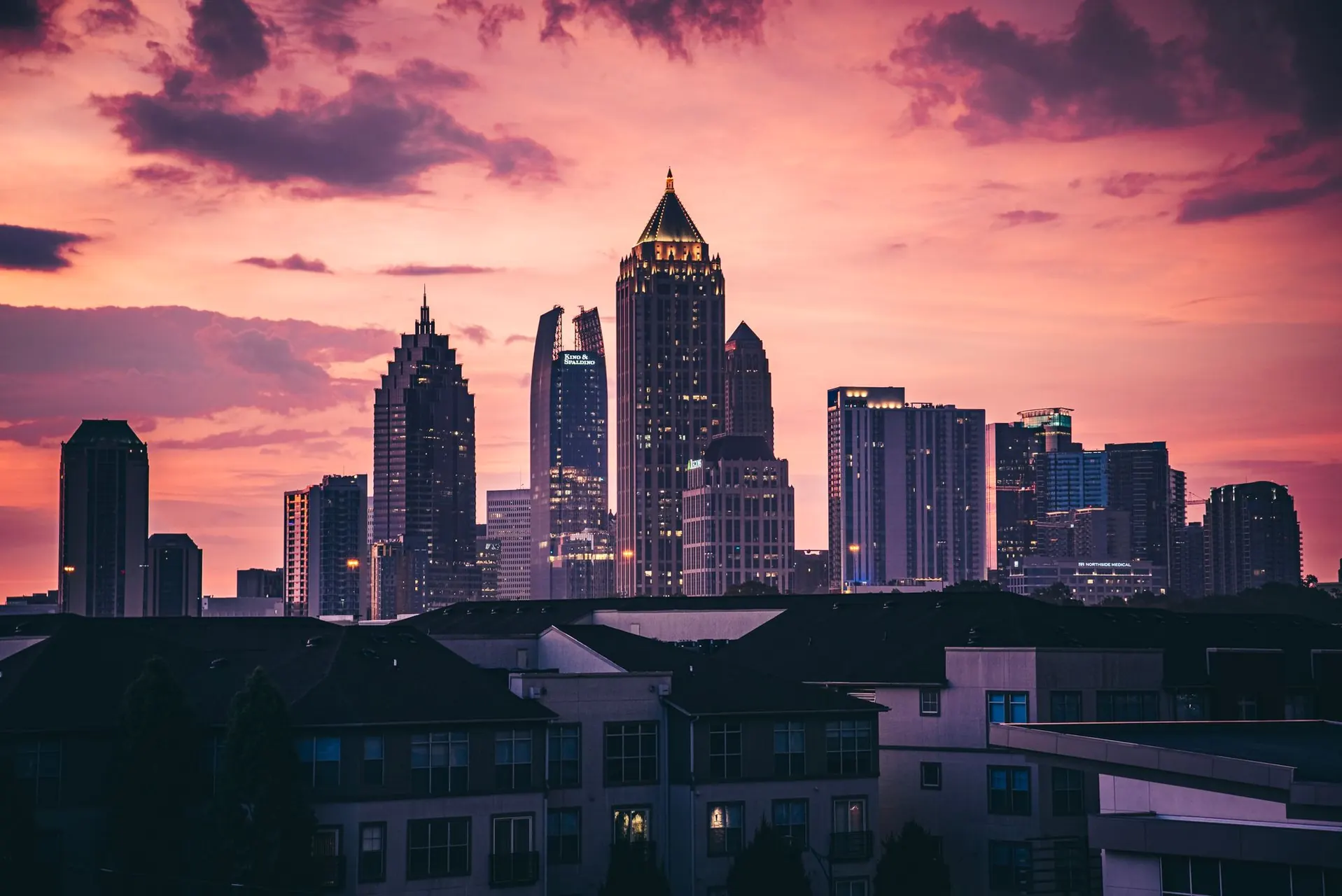 Midtown Atlanta towers against a pink and purple sunset.
