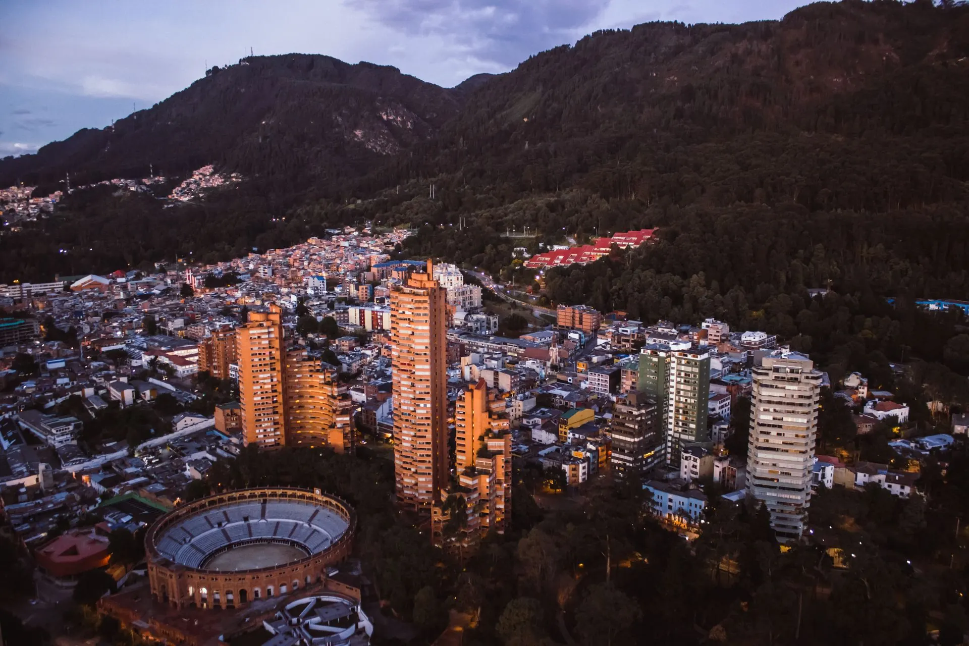 Bogotá at dusk, with apartment towers and the bullring below the dark slopes of the Andes.