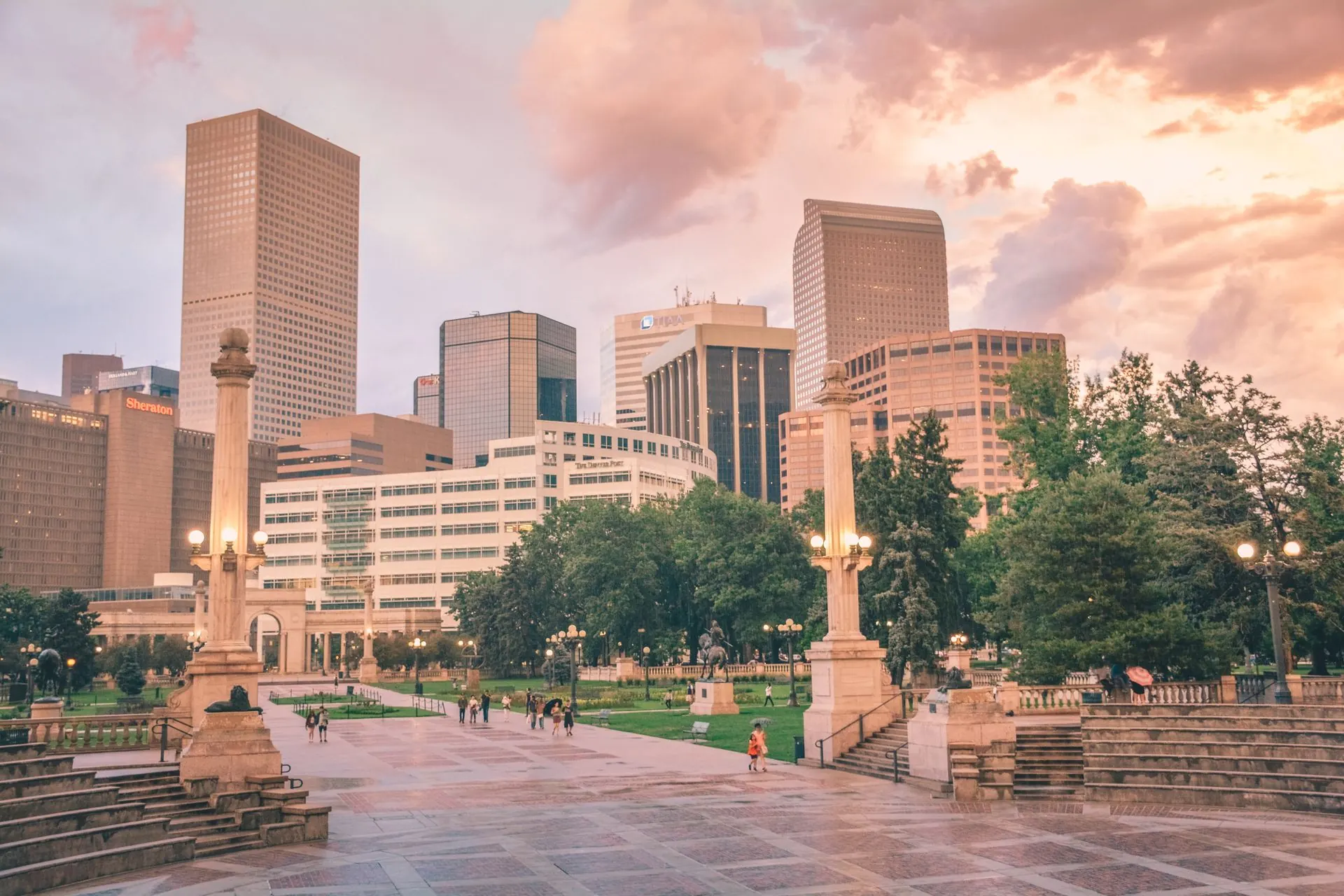 Civic Center Park in downtown Denver with office towers behind it in evening light.