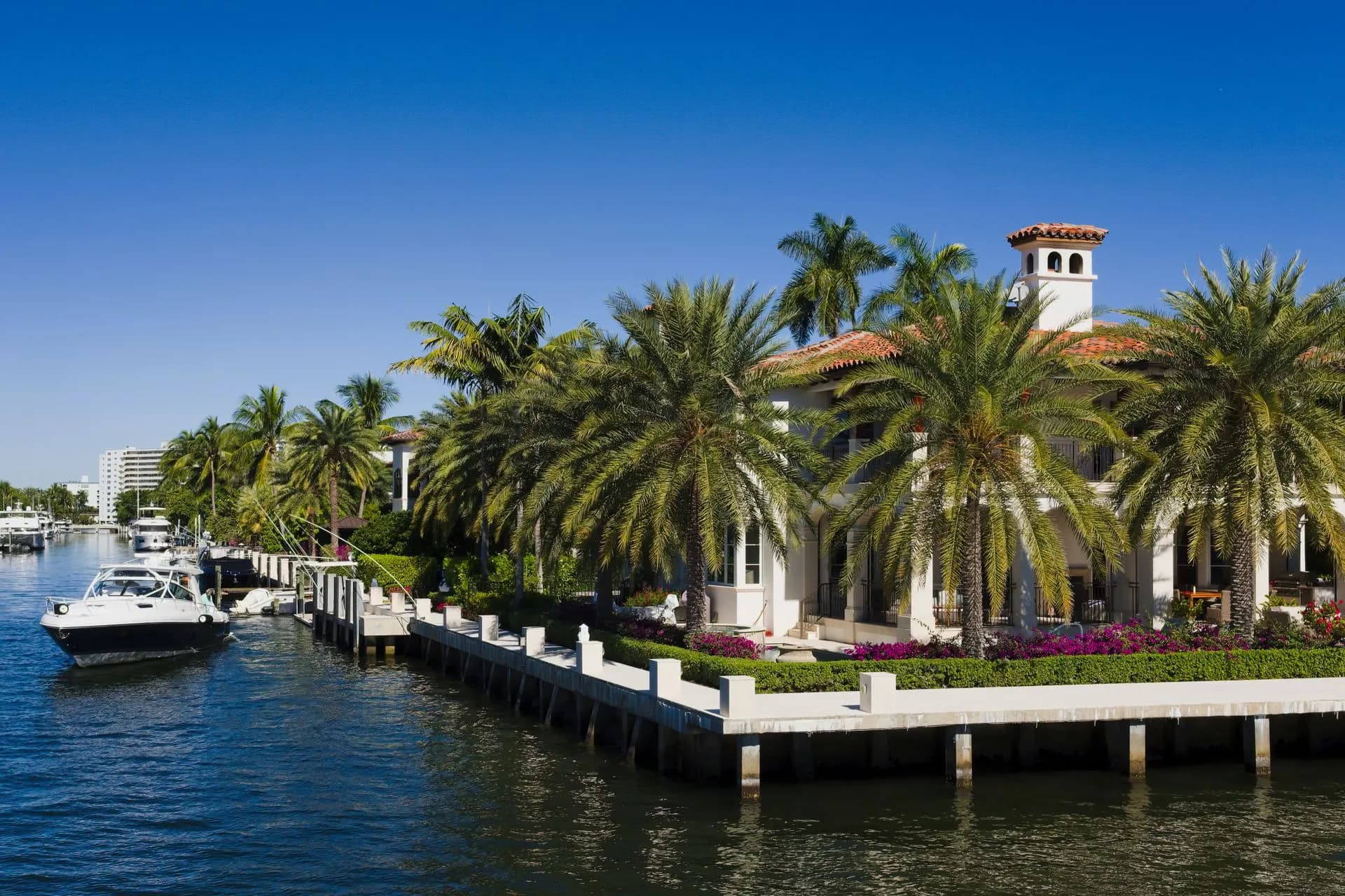A canal in Fort Lauderdale with yachts moored beside palm trees and waterfront homes.