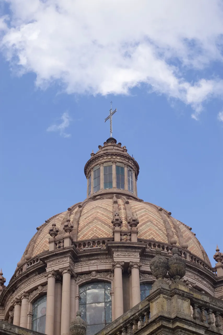 The dome and cross of Guadalajara Cathedral against a blue sky.