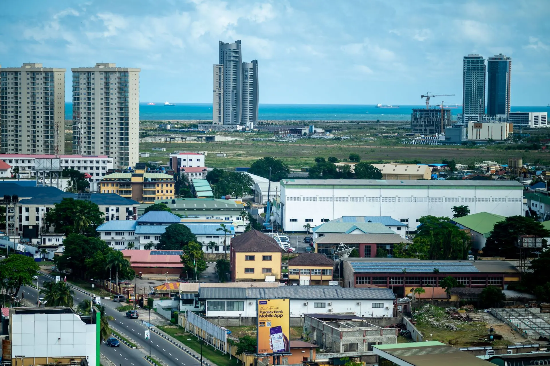 Lagos from above, with Victoria Island towers and the Atlantic on the horizon.