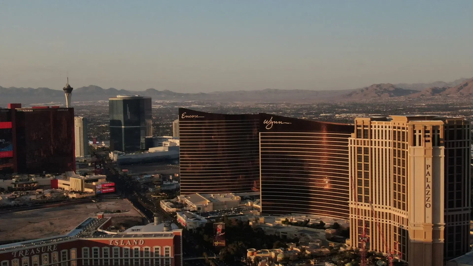 The Las Vegas Strip from the air at sunset, with resort towers and the desert mountains behind.