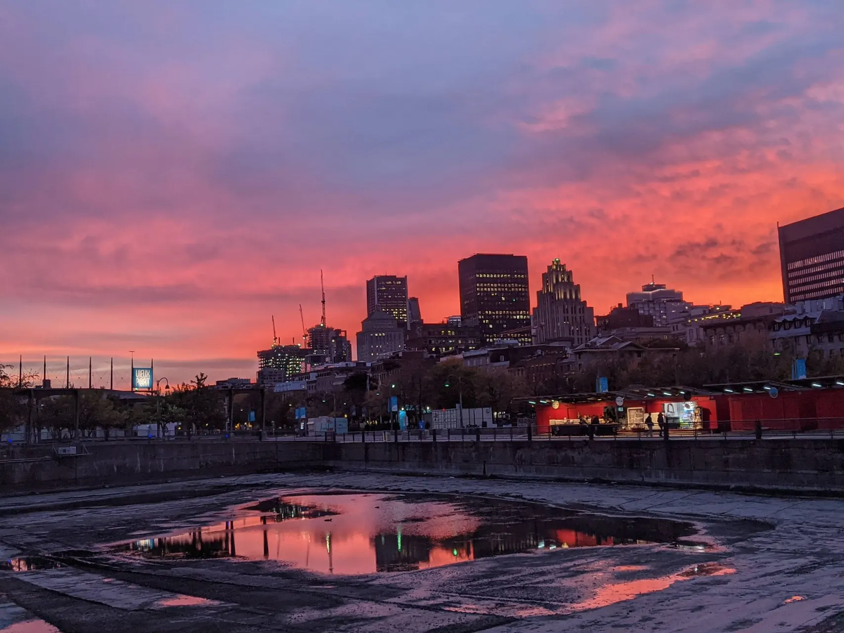 The Montreal skyline at sunset, with the sky reflected in water in the foreground.