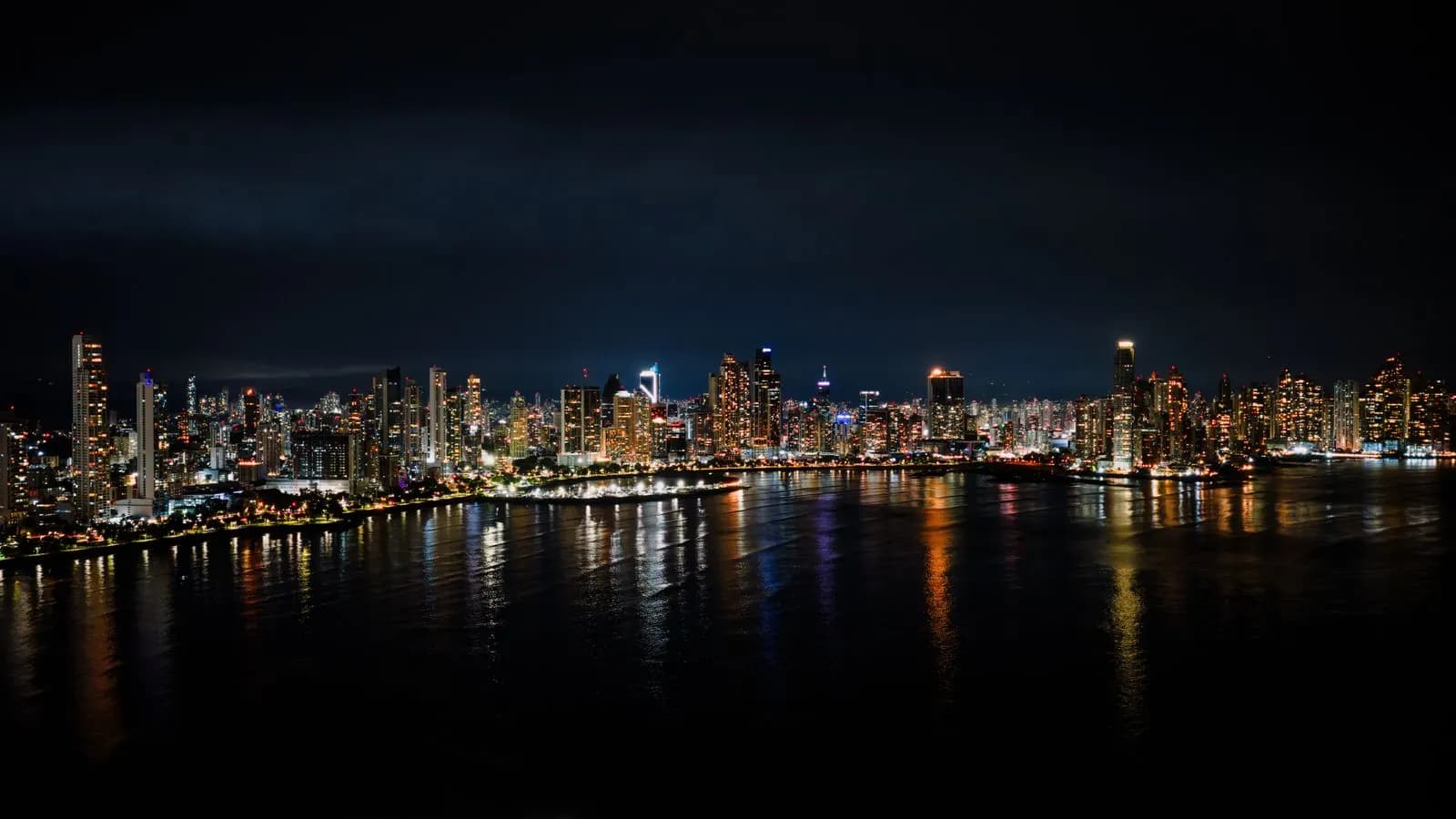 The Panama City skyline lit at night along the bay, seen from the water.